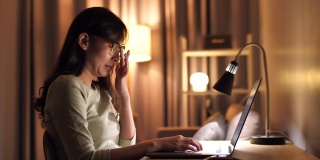 亚洲女性晚上在家里使用笔记本电脑