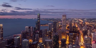 放大芝加哥天空中粉红色和蓝色的云漂浮在密歇根湖的水面上，以及市中心沿密歇根大道的高楼大厦。