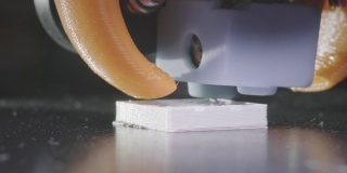 3D打印机从白色abs塑料中打印出一个抽象的立方体形状。3D打印机头在行动。一台自动三维3d打印机可以打印塑料。宏。