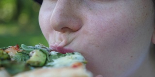 饥饿的女孩在吃一片素食披萨。闭上嘴。健康有机素食街头食品概念
