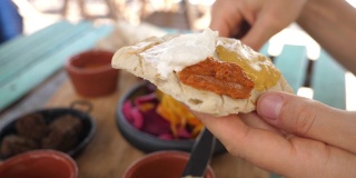 小菜吃早餐。用刀在刚烤好的皮塔饼上涂上不同的蘸料。中东健康有机素食菜肴