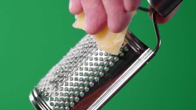 男性用手在磨碎机上擦帕尔马干酪。