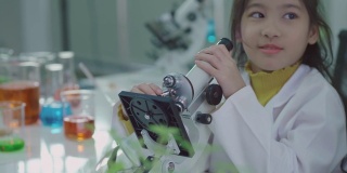 科学家用显微镜教亚洲小女孩在科学教室里，快乐的孩子和微笑在科学教室里