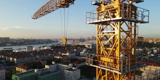 日落时分，无人机在工地吊车塔周围向上移动