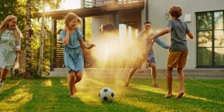 快乐的四口之家玩花园水管，互相喷水。阳光明媚的夏日，父亲、母亲、女儿和儿子在田园别墅的后院草坪上玩游戏
