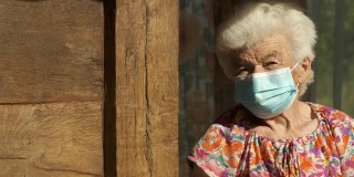 真实人物老年妇女戴口罩以避免传染病。看着相机微笑