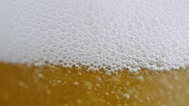 慢镜头的特写镜头，倒啤酒与泡沫和泡沫到一个杯子
