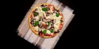 黑色混凝土背景上的披萨。马苏里拉奶酪、蘑菇、罗勒。为文本复制空间。从上面看，地势平坦