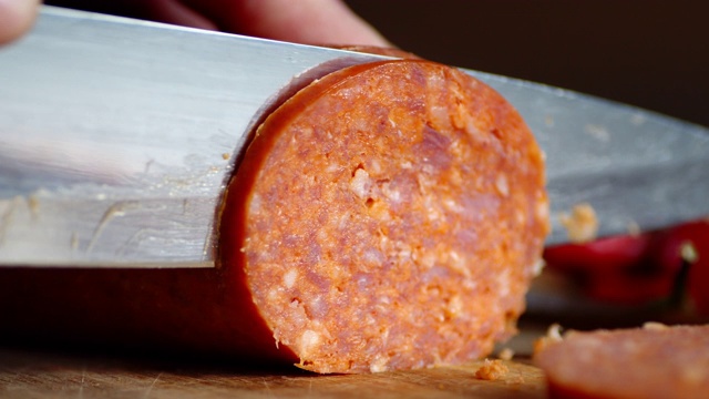 在砧板上把意大利香肠切成小块。