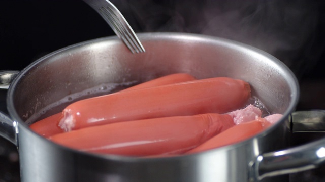 锅里煮熟的香肠用叉子搅拌一下。