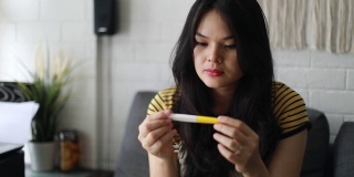 可悲的亚洲妇女正在用验孕棒怀孕