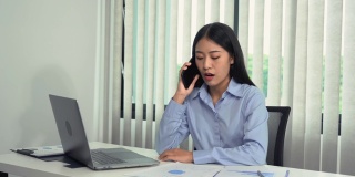 亚洲经理正在与一名员工通电话，对办公室错误的文书工作感到愤怒。