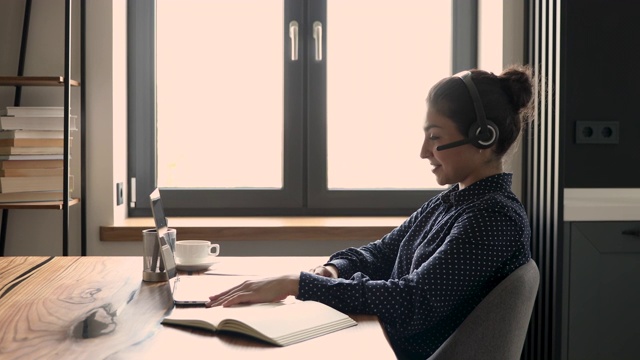女商人头戴耳机使用笔记本电脑视频通话应用程序与客户交谈