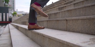 慢动作的双腿，自信的商人，办公室职员，穿着西装和皮鞋，在办公区域的高峰时间走上楼去工作。商人企业家在城市里爬楼梯。
