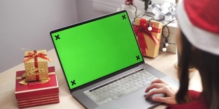 在圣诞活动中使用绿色屏幕笔记本电脑的女人