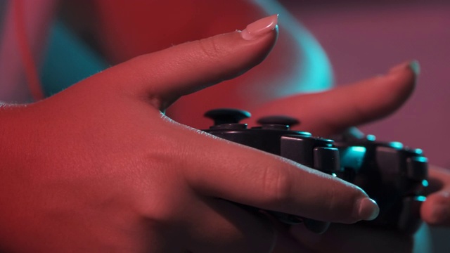 女人的手与游戏控制台控制器的特写，而玩。彩灯