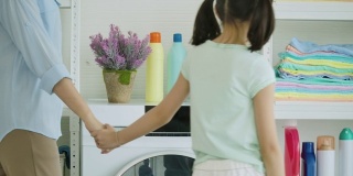 亚洲母亲和孩子洗衣服。妈妈和女儿有时间在家里一起打扫卫生。
