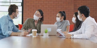 一群办公室工作人员在办公室开会并戴口罩，以保护新冠肺炎