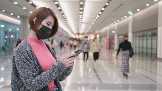 在机场戴口罩并使用智能手机的亚洲女性视频素材模板下载