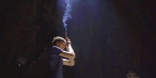 慢镜头拍摄的一个年轻的欧洲男子正在祈祷，手里拿着烟熏香棒