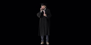 快乐毕业的年轻人戴着学位帽和长袍在手机上和父母聊天，阿尔法频道