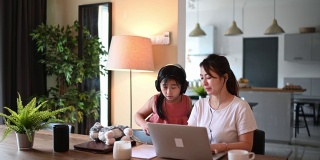 亚裔华人中年妇女在餐厅工作，用笔记本电脑打字，而她的女儿陪着她