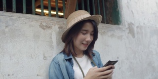 手持。快乐的亚洲年轻女子旅行者和使用智能手机在泰国曼谷老城区的街道上。假期中的单人旅行概念