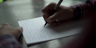 Kuchl /奥地利- 2019年8月22日:一名男子在棕色木桌上的白纸上书写信件。复古信，婚礼爱情故事，新郎誓言。缓慢的运动。关闭了。