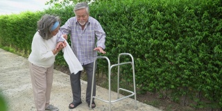 亚洲老夫妇与沃克在家里散步。一位老人和一位老妇人一起在公园里散步。成熟的丈夫和妻子共同支持花园