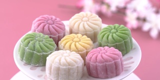 彩色的雪皮月饼，甜的雪月饼，传统美味的甜点中秋节在柔和的淡粉色的背景，近距离，生活方式。