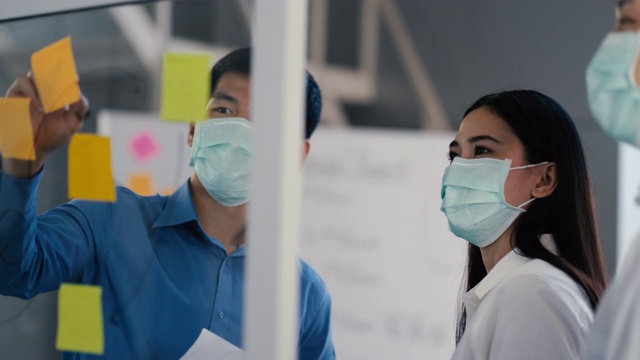 肖像组的亚洲在医疗标志在一个多样化的团队的创造性千禧同事在创业头脑风暴的策略。三个商务人士在办公室开会时一起工作。