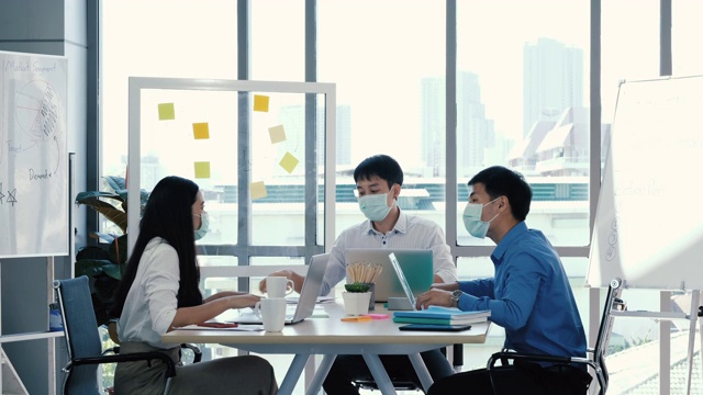 肖像组的亚洲在医疗标志在一个多样化的团队的创造性千禧同事在创业头脑风暴的策略。三个商务人士在办公室开会时一起工作。