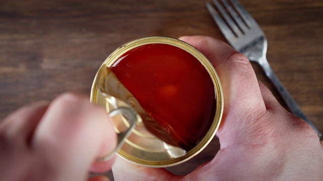 双手打开番茄酱豆罐头。