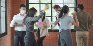 一群戴着口罩的工作人员在办公室一起跳舞、庆祝
