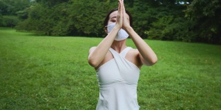 瑜伽教练带着防护口罩在公园里练瑜伽