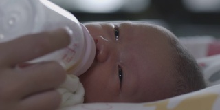 可爱的亚洲新生女婴正在吸奶瓶里的奶。母亲给新生儿喂奶。