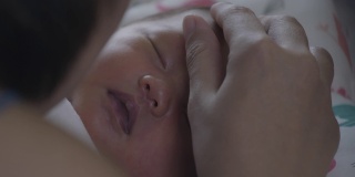 靠近可爱的亚洲新生女婴正在睡觉和母亲触摸她的脸与温柔和爱。幸福的家庭的概念。