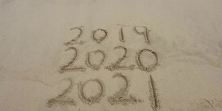 在美丽的海滩背景上的沙子上手写的2021年消息。新年的概念。
