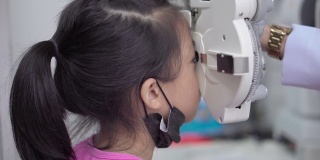 一个亚洲小女孩在诊所里用光镜检查眼睛