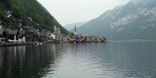 哈尔斯塔特-奥地利阿尔卑斯山脉之间的湖上的历史村庄。奥地利建筑，教堂和小教堂。灰色的多云的天空。山坡上的绿色森林。
