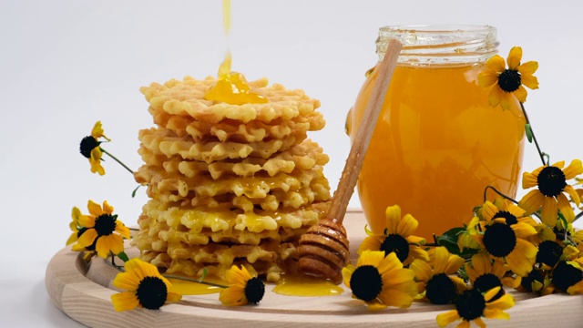 蜂蜜倒在华夫饼上。美味健康的早餐配比利时华夫饼
