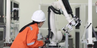 专业人员检查机器人在制造工厂的夹具基地上移动。在实验室修理机械臂，佩戴护目镜，使用控制器或机器人控制面板。