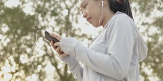 亚洲女性跑步运动员用智能手机听音乐。