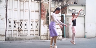 侧视图:年轻的女芭蕾舞老师在当地的街道和旧建筑作为教室，教学生带领白人青少年芭蕾舞者练习芭蕾舞。概念活泼的年轻妇女和孩子在周末的活动。