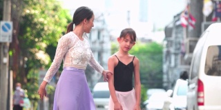 在一个阳光明媚的日子里，年轻的女芭蕾舞老师教学生，白种青少年芭蕾舞者在曼谷的一间教室里练习芭蕾舞。活跃的年轻妇女和孩子的概念周末活动和当地地标。