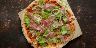 美味的披萨配上意大利熏火腿、帕尔玛火腿、芝麻菜沙拉和芝麻菜