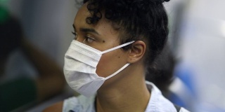 年轻女子戴着医用口罩乘坐地铁。乘地铁上下班的学生或工人望着窗外