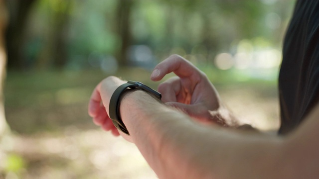 男人使用智能手表可穿戴腕带设备。近触屏可穿戴技术智能腕带户外。男性脉搏检测智能手表App