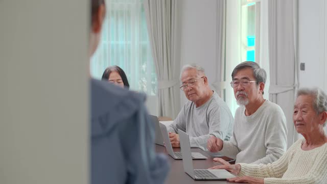 一群年龄在60-70岁之间的亚洲高年级学生，他们参加初级计算机培训课程，作为他们老年教育的一部分。成人语言学习概念。