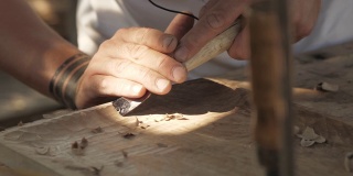 木雕师用凿子加工胡桃木板。工匠在做一个茶盘